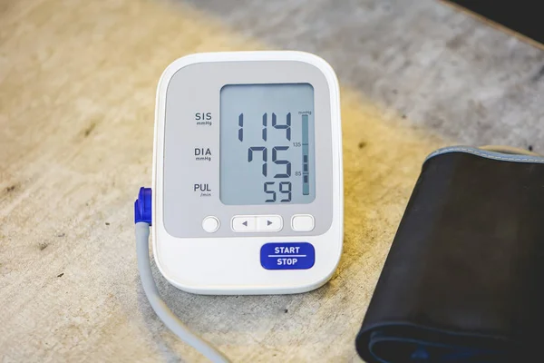 Electronic blood pressure monitor on wooden table background